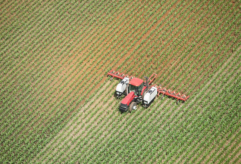 Birds eye view of a tractor in a field collecting crops