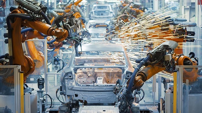 Robotic arms working to resemble cars in an automotive plant