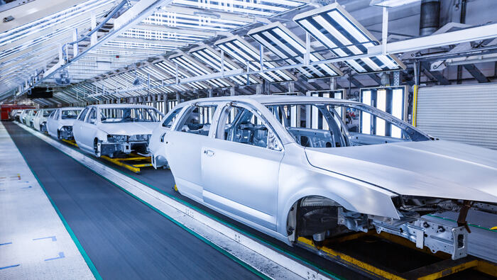 Cars are being assembled in a row at a car plant.